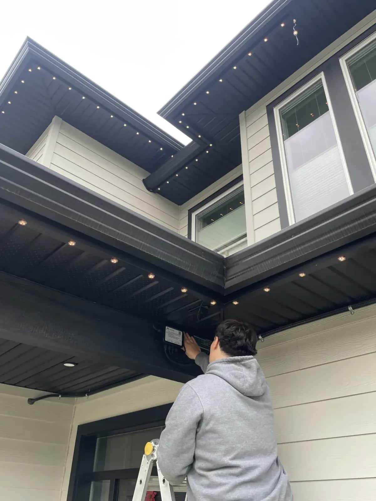 Forever Lights technician installing a permanent LED lighting controller under the soffit of a home