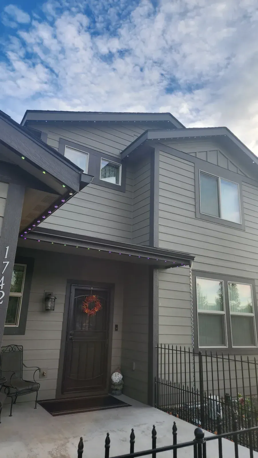 Grey two-storey home in daylight showing how the permanent LED track disappears against the soffit and fascia